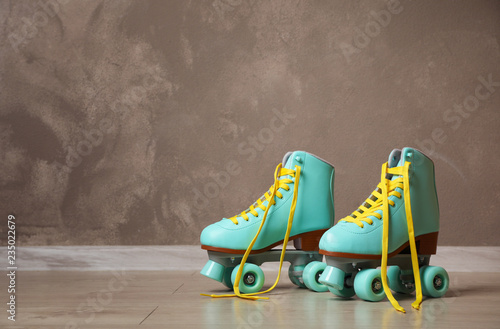 Obraz na plátne Vintage roller skates on floor near brown wall. Space for text