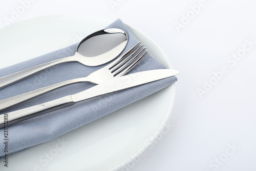 Plate with cutlery and napkin on white background, closeup