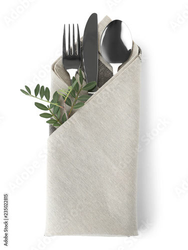 Folded napkin with fork, spoon and knife on white background, top view