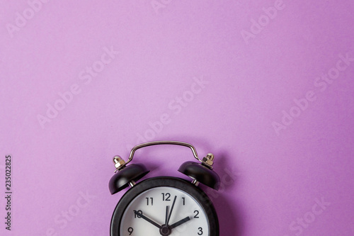 Ringing twin bell vintage classic alarm clock Isolated on purple violet pastel colourful background. Rest hours time of life good morning night wake up awake concept. Flat lay top view copy space photo