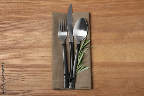 Cutlery and linen napkin on wooden background, top view