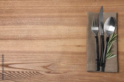 Cutlery and linen napkin on wooden background, top view. Space for text