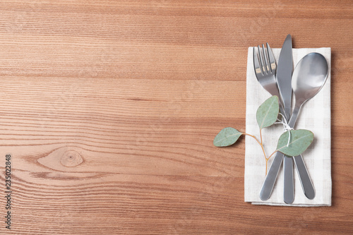 Napkin with fork, spoon and knife on wooden background, top view. Space for text