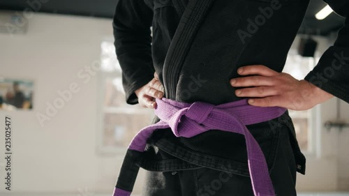 Karate purple belt tied around marital artists torso wearing black dojo GI's jiu jitsu mma fighter wearing gym ring photo