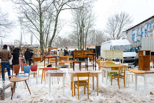 Atmosphere of people shopping second hand vintage furnitures, clothes and stuffs show on the ground covered with snow at Fleamarket at Mauerpark in winter season. © Peeradontax