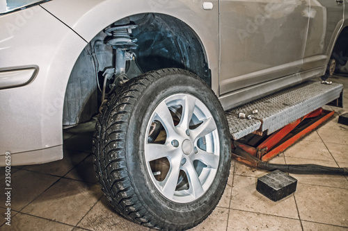 Car in garage of auto repair service shop with special repairing equipment for replacement tire wheels