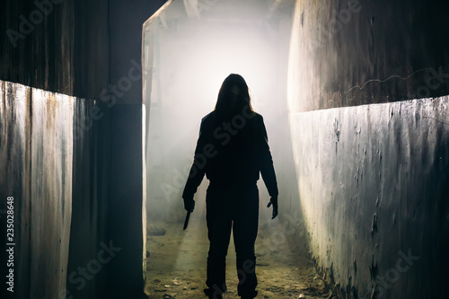 Foto Silhouette of man maniac or killer or horror murderer with knife in hand in dark creepy and spooky corridor