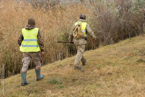 Hunter with a gun and a dog go on the first snow in the steppe, Hunting pheasant in a reflective vest