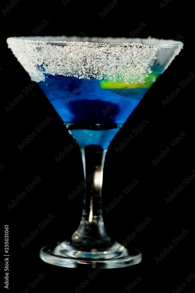 Blue kamikaze cocktail with vodka, lime juice, blue curacao, sugar and lime wedge