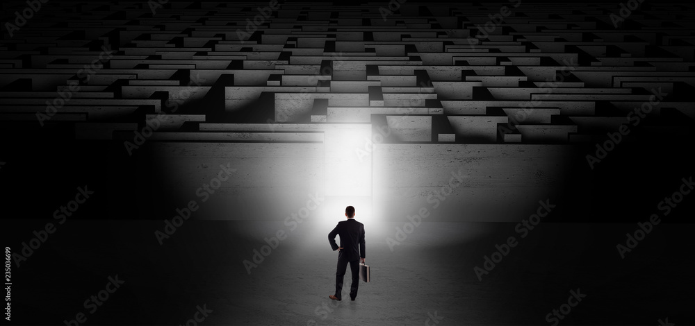 Businessman getting ready to enter the dark labyrinth with illuminated door
