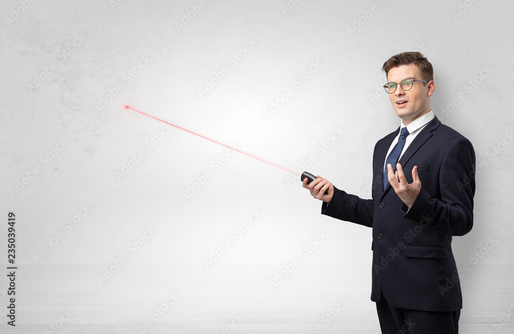 Young businessman with laser pointer and copyspace white wall
