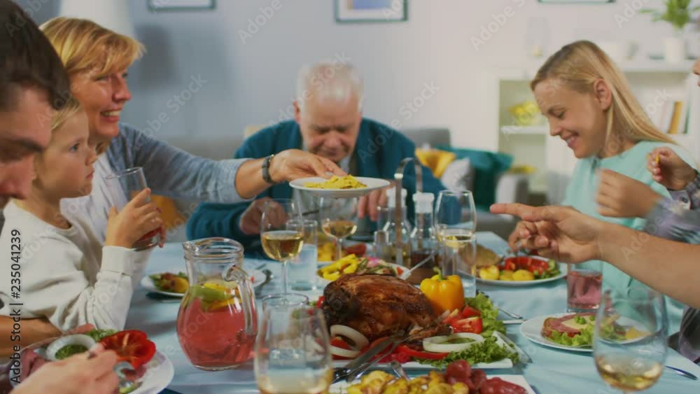 Big Family and Friends Celebration at Home, Diverse Group of Young and Old People Gathered at the Table. Eating, Sharing Meals, Drinking and Having Fun. Daytime Festivity. Big Family and Friends Celebration at Home, Diverse Group of Young and Old People Gathered at the Table. Eating, Sharing Meals, Drinking and Having Fun. Daytime Festivity.