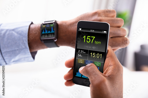 Man With Smartwatch And Cellphone Showing Heartbeat Rate