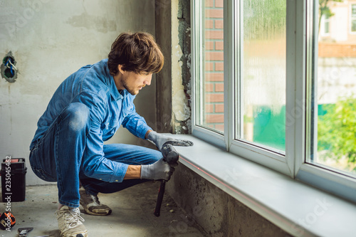 Man in a blue shirt does window installation photo