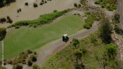 A golfer getting ready to tee off with his golf cart on the green.