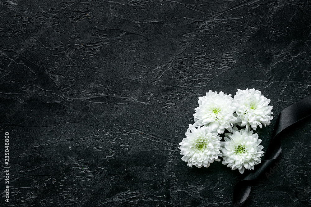 Funeral symbols. White flower near black ribbon on black background top