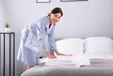 Housemaid Placing Flowers On Stack Of Towels