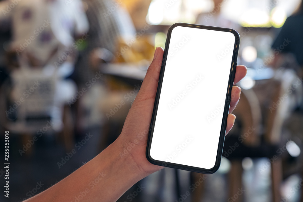 Mockup image of a hand holding black mobile phone with blank desktop screen with blur background in cafe Mockup image of a hand holding black mobile phone with blank desktop screen with blur background in cafe