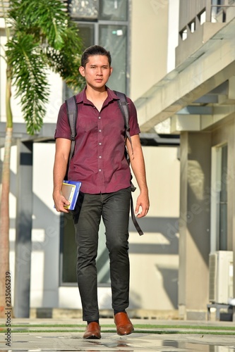 Unemotional Youthful Filipino Student With Books Walking On Campus