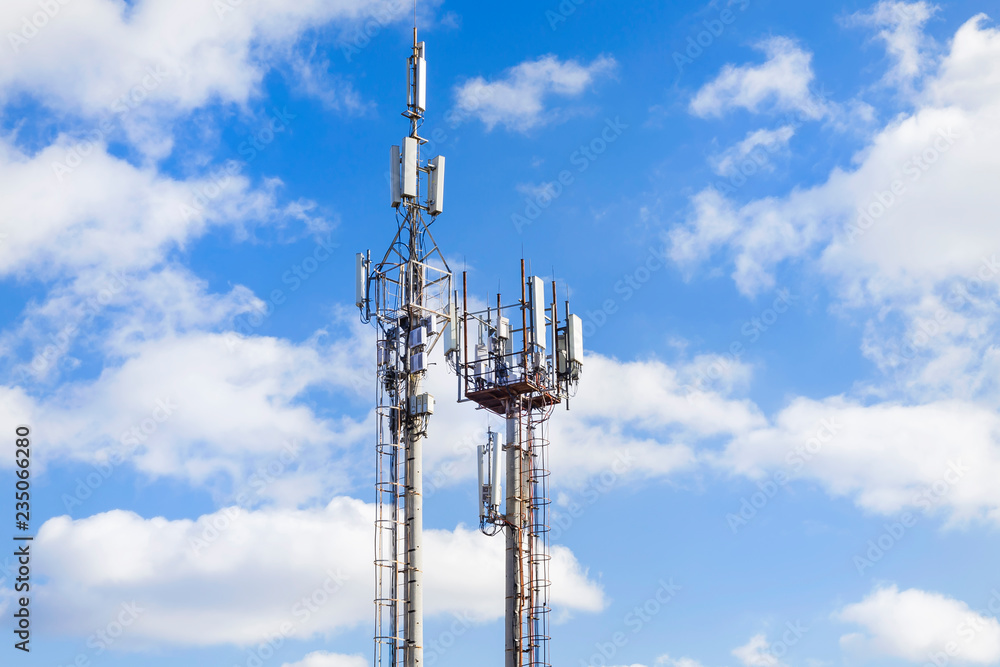 Two cell towers against the blue sky with clouds. Mobile communications and communications.