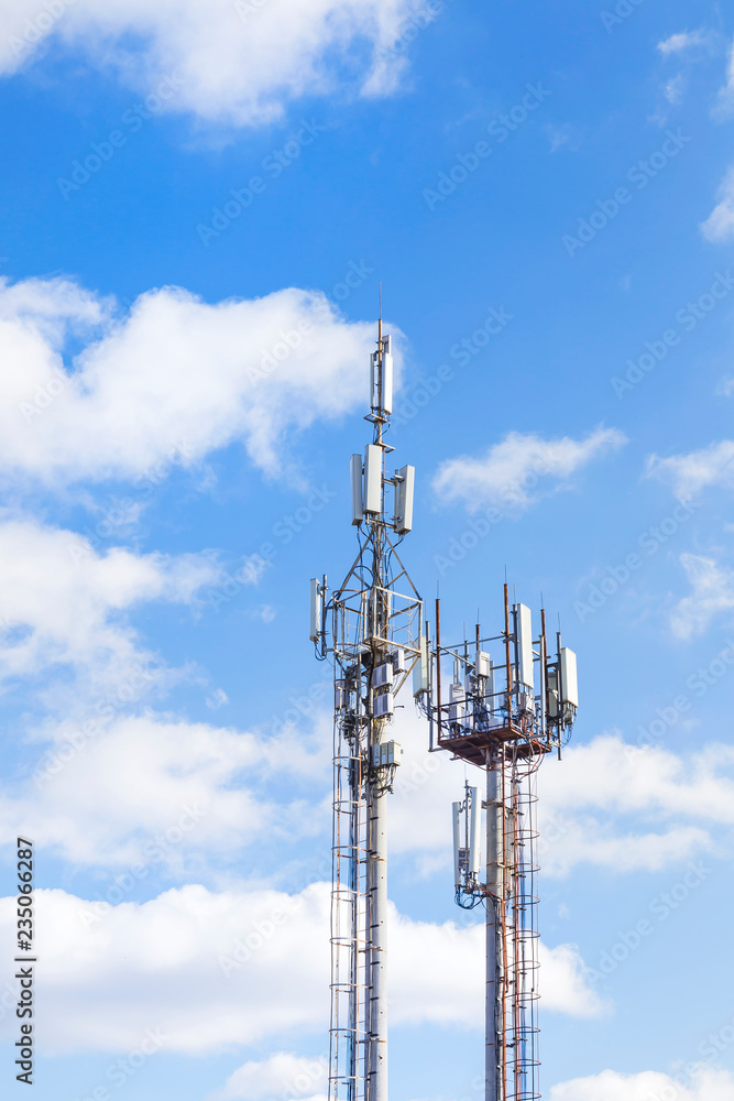Two cell towers against the blue sky with clouds. Mobile communications, telephone network and communications.
