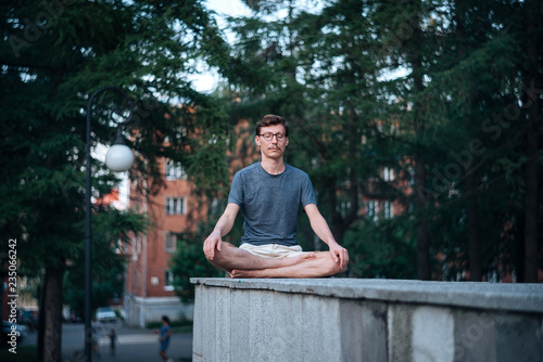 Man practicing meditation in city.