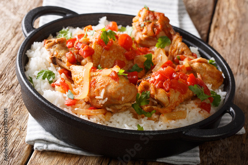 Haitian recipe for spicy chicken cooked in vegetable sauce with white wine served with white rice in a frying pan closeup. horizontal