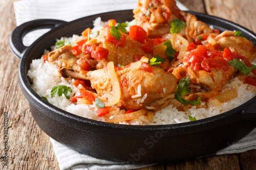 Haitian chicken stewed in a spicy tomato sauce served with white rice close-up in a pan. horizontal