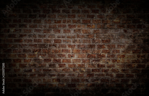 darkness theme. background and wallpaper or texture which has dim light of dark discolored old brick wall ancient vintage retro style have damage and cracks.
