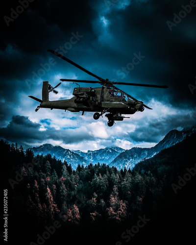 Heavy armed attack helicopter flies over hills