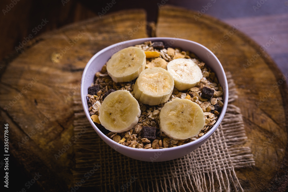 Bowl of cereal with fruit, pieces of banana with oats and cereal.