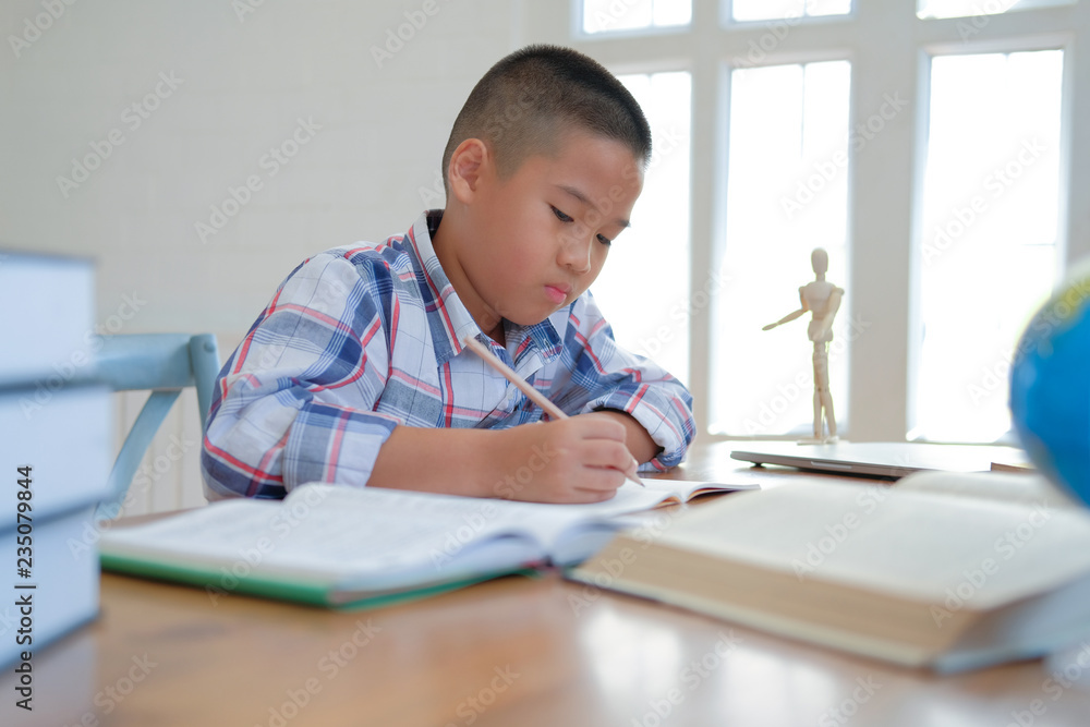 little asian kid boy schoolboy writing drawing on notebook. child children doing homework. little asian kid boy schoolboy writing drawing on notebook. child children doing homework.