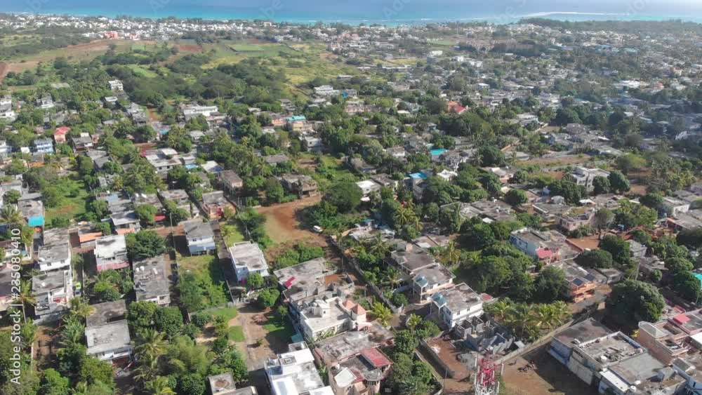 Aerial view of Triolet town, Mauritius, with a smooth camera tilt to reveal the urban landscape and the sea, during a sunny day. Aerial view of Triolet town, Mauritius, with a smooth camera tilt to reveal the urban landscape and the sea, during a sunny day.