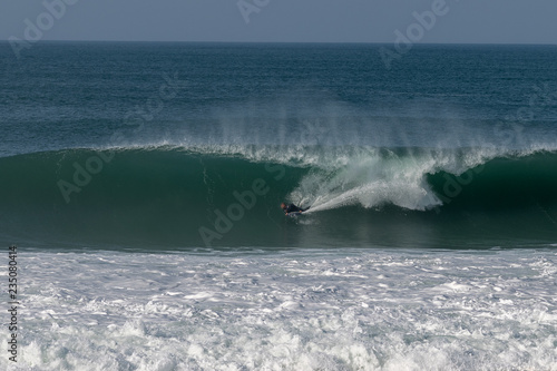 Surfer on Atlantic ocean wave , Nazare , Portugal.
