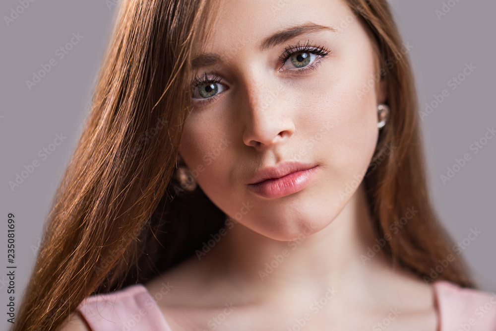 Fototapeta premium Horizontal closeup portrait of a beautiful young woman with clean skin, long eyelashes and natural beauty, fresh face. Green eyes, charming girl's