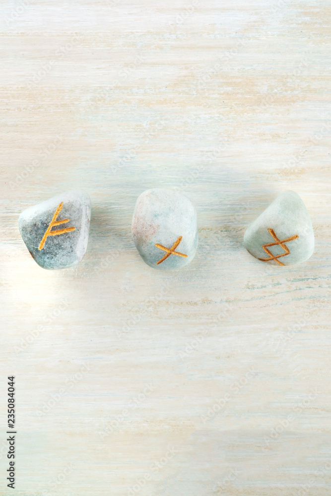 Norse runes, stones with symbols used in Wiccan and other magic and for divination, shot from the top on a light background with a place for text Norse runes, stones with symbols used in Wiccan and other magic and for divination, shot from the top on a light background with a place for text