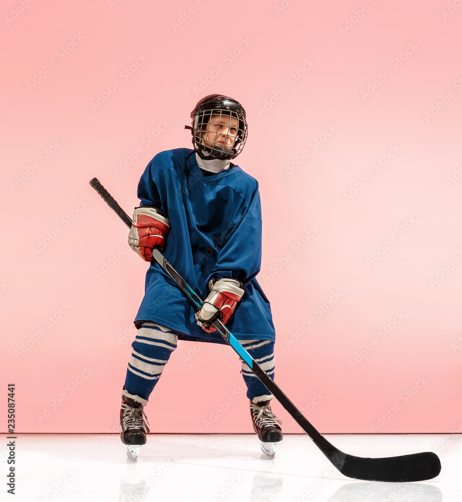 A hockey player in uniform with equipment over pink studio background. The athlete, child, sport, action concept A hockey player in uniform with equipment over pink studio background. The athlete, child, sport, action concept