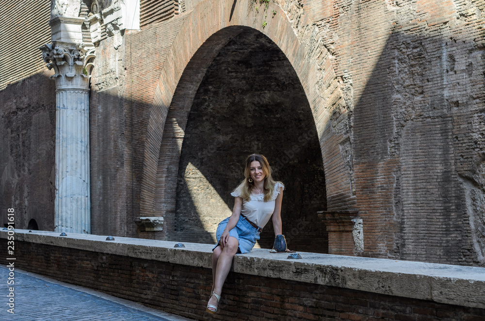Young charming girl sits on the parapet on the ruins of the Pantheon in Rome, Italy