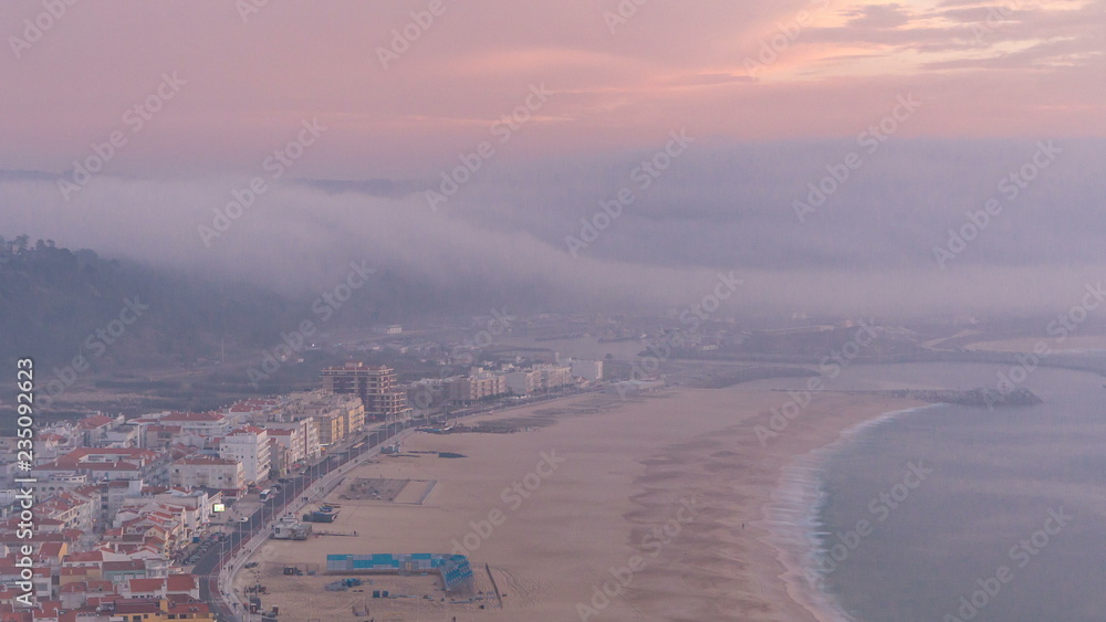 Obraz premium View of Nazare panorama with cabins of Funicular timelapse. Fog coming from ocean at evening during sunset.