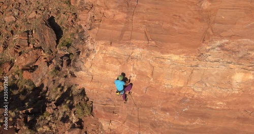 Aerial shot of rock climber reaching for hand hold photo