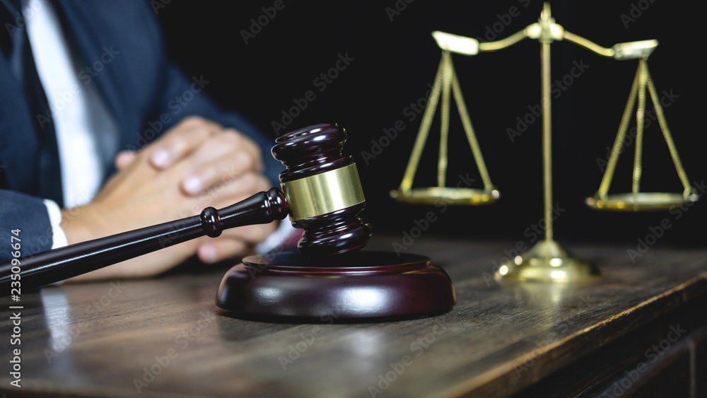 Legal law, advice and justice concept, male counseling lawyer or notary working on a documents and contract papers of the important case and wooden gavel, brass scale in courtroom Legal law, advice and justice concept, male counseling lawyer or notary working on a documents and contract papers of the important case and wooden gavel, brass scale in courtroom
