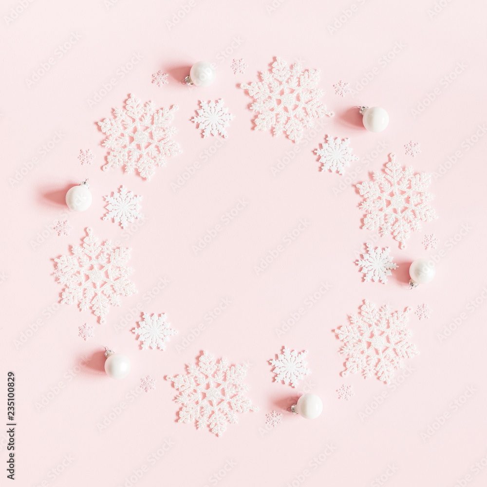 Obraz premium Christmas or winter composition. Wreath made of white balls and snowflakes on pastel pink background. Christmas, winter, new year concept. Flat lay, top view, copy space, square