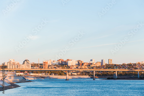 Cityscape, blue river and bridge on high apartments and buildings