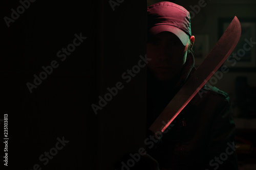 Image of killer with machete in dark apartment with red light