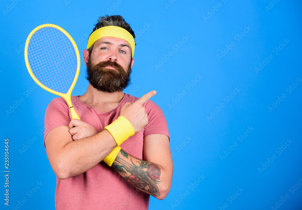 Athlete hold tennis racket in hand on blue background. Tennis sport  advertisement. Tennis club concept. Man bearded hipster wear old school  sport outfit with bandages. Tennis player retro fashion Stock Photo