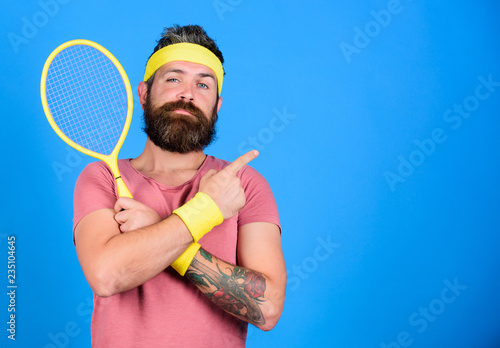 Athlete hold tennis racket in hand on blue background. Tennis sport advertisement. Tennis club concept. Man bearded hipster wear old school sport outfit with bandages. Tennis player retro fashion © be free