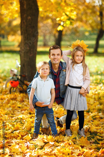Image of father with daughter and son in autumn park walking