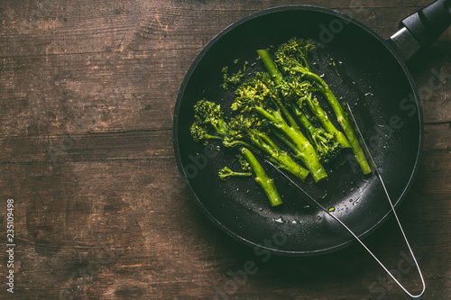 Konstfotografi Blanched broccoli in black cooking pan on wooden background, top view with copy space