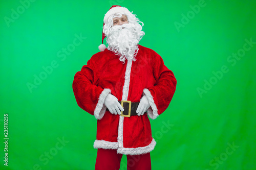 Traditional Santa Claus standing holding his belt on green background