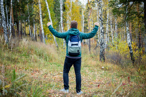 Happy male hiker has raised his hands in success